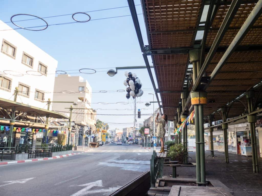 Woman letting balloons fly on the main shopping street, Tiberias, Sea of Galilee, Israel (2017-01-20)