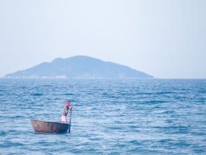 Fisherman with traditional round boat off the beach, Hoi An, Vietnam (2017-05/06)