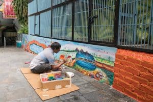 Man painting colorful murals at Cave Villa, Batu Caves, Kuala Lumpur, Malaysia - 20171231-DSC03289